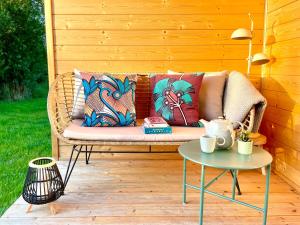 a wicker couch on a patio with a table at 208 Gemütliches Tiny House mit Blick ins Grüne in Bleckede