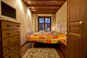 a bedroom with a bed and a dresser and a television at Apartarent 1500 - Apartamento Gamo in Baqueira-Beret