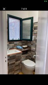 Un baño con inodoro, lavabo y ventana. en casa dragonetti, en Marina di Ragusa