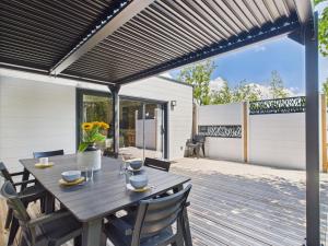 a wooden deck with a table and chairs under a black pergola at Résidence Les Voiles Blanches - Chalet pour 8 in Saint-Gilles-Croix-de-Vie