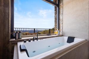 a bath tub in a bathroom with a large window at Petres Luxury Villas with heated private pool in Agia Galini