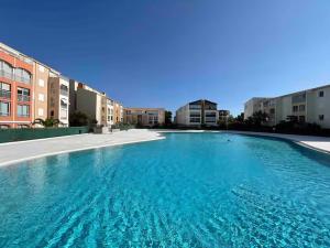 a large blue swimming pool in front of some buildings at Jacuzzi, massage et plage ! in Fréjus