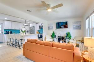 a living room with an orange couch and a kitchen at Private Hot Tub and Fenced Yard Sleek Gulfport Home in St Petersburg