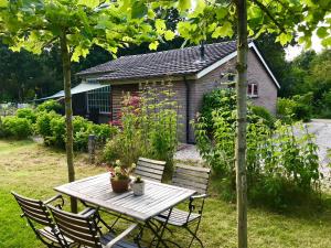 a wooden table and chairs in a garden at Bungalow de Mees in Schoonloo