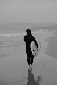 a woman walking on the beach with a surfboard at Amoha Surf & Yoga - Boutique Mountain Location in Taghazout