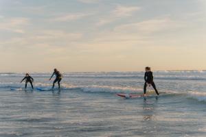 three surfers are riding the waves on the beach at Amoha Surf & Yoga - Boutique Mountain Location in Taghazout