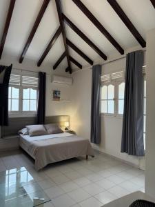 a bedroom with a large bed and windows at Résidence O Gosier in Le Gosier