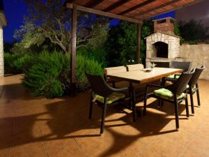 Una mesa y sillas de madera en un patio con chimenea. en Apartments Jobst, en Vela Luka
