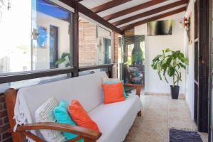 a white couch with colorful pillows on a porch at Casa Ilhadelas in Ilhabela