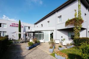 a white building with plants in a courtyard at Hôtel & Résidence Octel in Portet-sur-Garonne