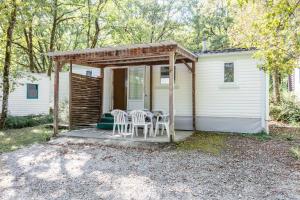a patio with a table and chairs on a house at Camping Au Bois Dormant in Chauffour-sur-Vell