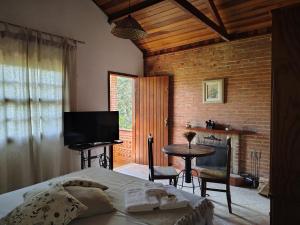 a bedroom with a bed and a television and a table at Pousada dos Pássaros in Santo Antônio do Pinhal