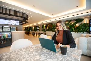eine Frau sitzt mit einem Laptop an einem Tisch in der Unterkunft La Residence Panamá in Panama-Stadt