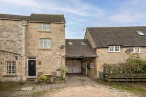una vecchia casa di mattoni con un vialetto di fronte di Evenlode Cottage a Stow on the Wold