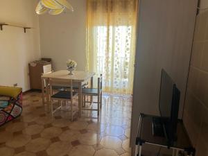 a living room with a table and chairs and a television at Holiday residence Sole San Marco in Calatabiano