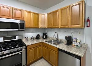 a kitchen with wooden cabinets and a stove and a sink at Apartamento acogedor in Jersey City