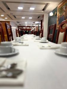 a long table with chairs and cups and saucers at Avraham Hotels in Machu Picchu
