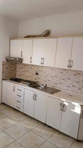 a kitchen with white cabinets and a sink at Qetesia Apartment in Shkodër
