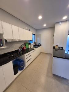 a kitchen with white cabinets and black counter tops at Tu casa moderna con Quincho in Asuncion