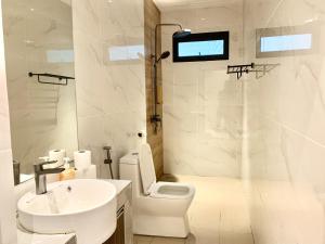 a white bathroom with a toilet and a sink at Deco Home The Summit Mesilau at Kundasang in Kundasang