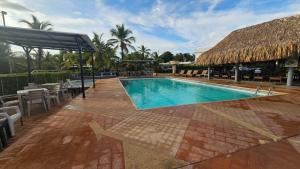 a swimming pool at a resort with a thatch roof at Cabañas Ana Sofía in San Antero