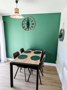 a dining room table with chairs and a clock on the wall at La maison au bord de la riviére in Loches