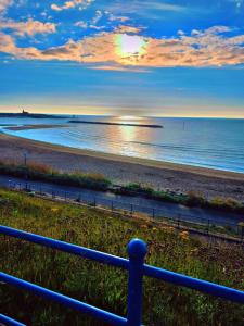 a view of a beach with the sun setting over the water at Marine Cottage 2 - With Private Hot Tub in Newbiggin-by-the-Sea