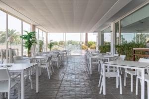 a restaurant with white tables and chairs and windows at Hotel Atlántico in Zahara de los Atunes