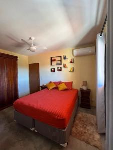 Schlafzimmer mit einem Bett mit roter Bettwäsche und gelben Kissen in der Unterkunft Casa no Centro Próxima ao Thermas Water Park in Águas de São Pedro