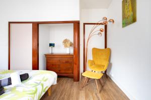 a bedroom with a yellow chair next to a bed at Two room apartment - centre historique in Mulhouse