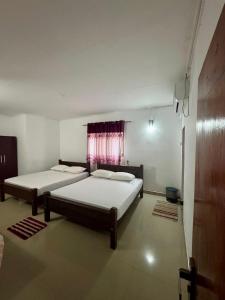 een slaapkamer met twee bedden en een raam bij Nimsara Holiday Resort in Anuradhapura +23 foto's