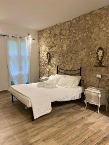 a bedroom with a large bed and a stone wall at Dani's House Holiday - Casa vacanza con vasca idromassaggio nel cuore di Cagliari in Cagliari