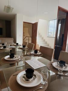 a dining room with a glass table with plates and cups at Duplex panorâmico in Vitória da Conquista
