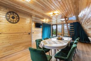 a dining room with a table and green chairs at NordiKaban A-Frame Vatra Dornei in Ortoaia
