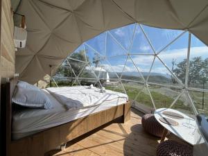 a bed in a tent with a large glass window at Nikorstminda glamping - Batoni's forest in Ambrolauri