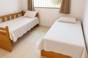 a room with two beds and a window at Apartamento charmoso 3/4 in Ilhéus