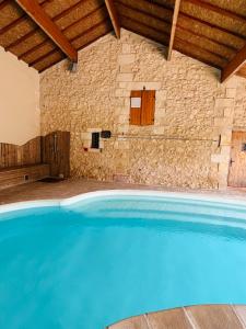 a large blue swimming pool in a stone building at Maison Aubergerac in Bergerac