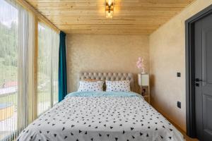 a bedroom with a bed and a large window at NordiKaban A-Frame Vatra Dornei in Ortoaia