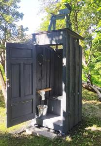 a black outhouse with a toilet in the grass at Minimalist riverside hideout in Riga +4 photos