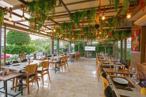 a restaurant with wooden tables and chairs and plants at Citrus Park Hotel in Antalya