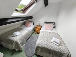 zwei Betten in einem Zimmer mit zwei Fenstern in der Unterkunft Linhay -Farm Cottage in Sidmouth