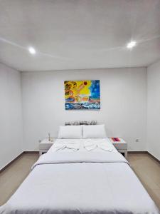 a bedroom with a large white bed with a painting on the wall at Bilene Harmony Home in Vila Praia Do Bilene