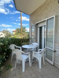 a patio with white chairs and a table and a window at Casa Giacinti in Falerone