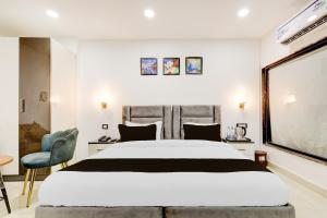 a bedroom with a large white bed and a chair at Townhouse The Grand Villa in New Delhi