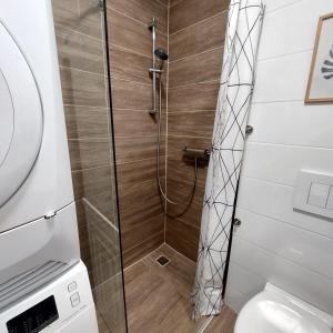a shower with a glass door next to a toilet at Skandi Garzon in Dunaújváros +8 photos