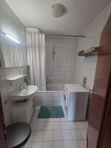 y baño con bañera, lavabo y lavadora. en SkyStay Modernes Apartment Messe&Flughafen, en Filderstadt 9 fotos más