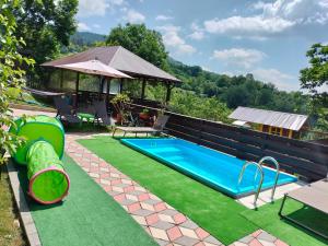 a backyard swimming pool with artificial grass and a gazebo at Casa Savu Secaria in Secăria