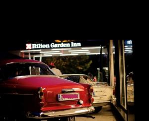 an old red car parked in front of a fusion garden inn at Hilton Garden Inn Tirana in Tirana