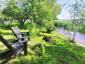 a wooden bench sitting in the grass next to a river at Minimalist riverside hideout in Riga