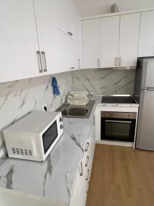 a white kitchen with a microwave and a sink at Cameria in Durrës